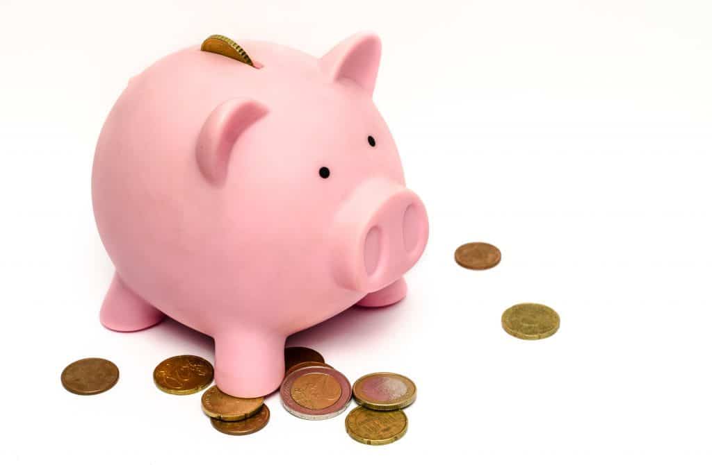 A cute pink piggy bank is surrounded with coins.